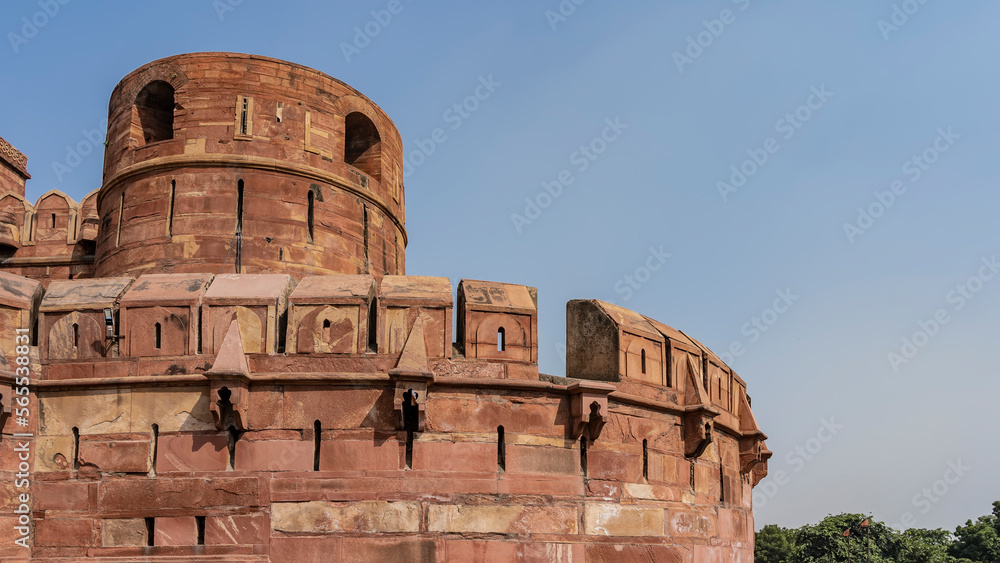 A fragment of the brick fortress wall of the ancient Red Fort. Towers, loopholes, windows are visible against the blue sky. India. Agra