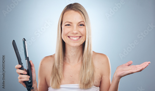 Face portrait, hair straightener and woman in studio with product placement isolated on a gray background. Beauty, haircare and female model advertising or marketing flat iron for salon treatment.