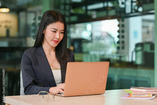 Positive focused Mature Business lady working with laptop at table in Co working space.