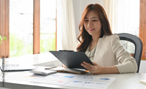 Administrator, businesswoman, Internal Revenue or financial inspector reading a report, calculating balance and Check the correctness of the document.
