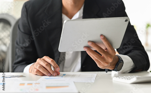 Close up of Administrator, businessman, Internal Revenue or financial inspector using tablet making report, calculating balance, checking document.