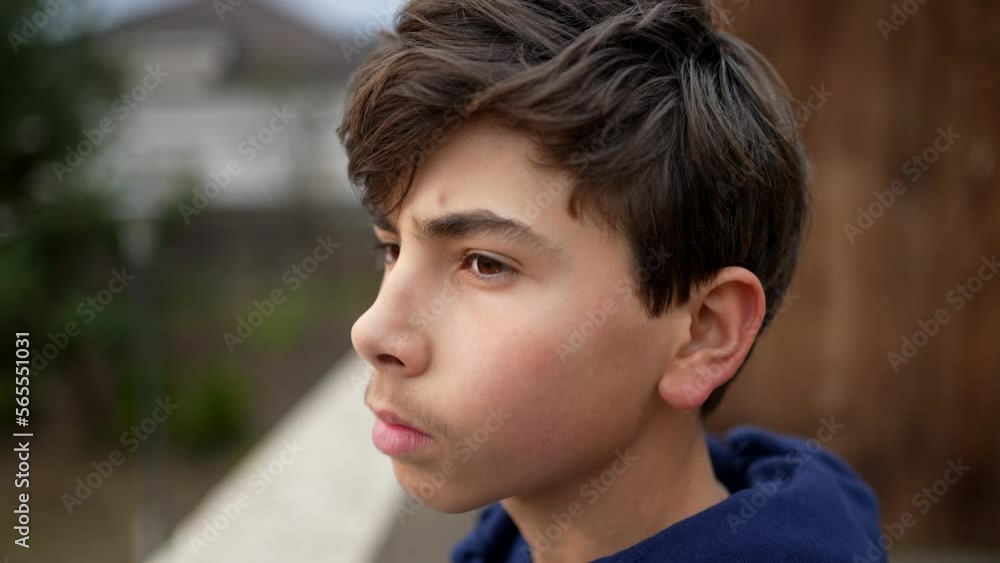 Teen kid stands at park outside staring at horizon in meditation. Tracking shot of young boy in contemplation Teen kid stands at park outside staring at horizon in meditation. Tracking shot of young boy in contemplation