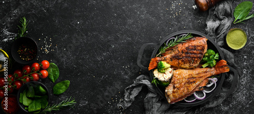 Fotografija Baked red fish perch with vegetables on a black stone plate