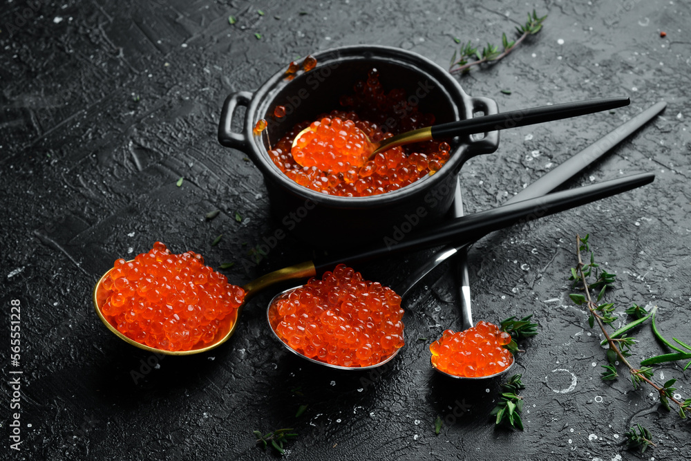 Red caviar in a spoon. High-quality caviar. On a black background. Free space for text. Red caviar in a spoon. High-quality caviar. On a black background. Free space for text.