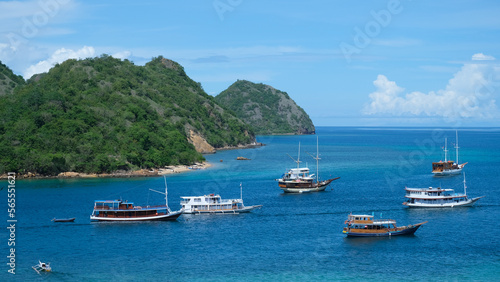 Landscape view of tropical islands with white sandy beaches and moored liveaboard tour boats in turquoise ocean in Labuan Bajo, Flores Island Indonesia