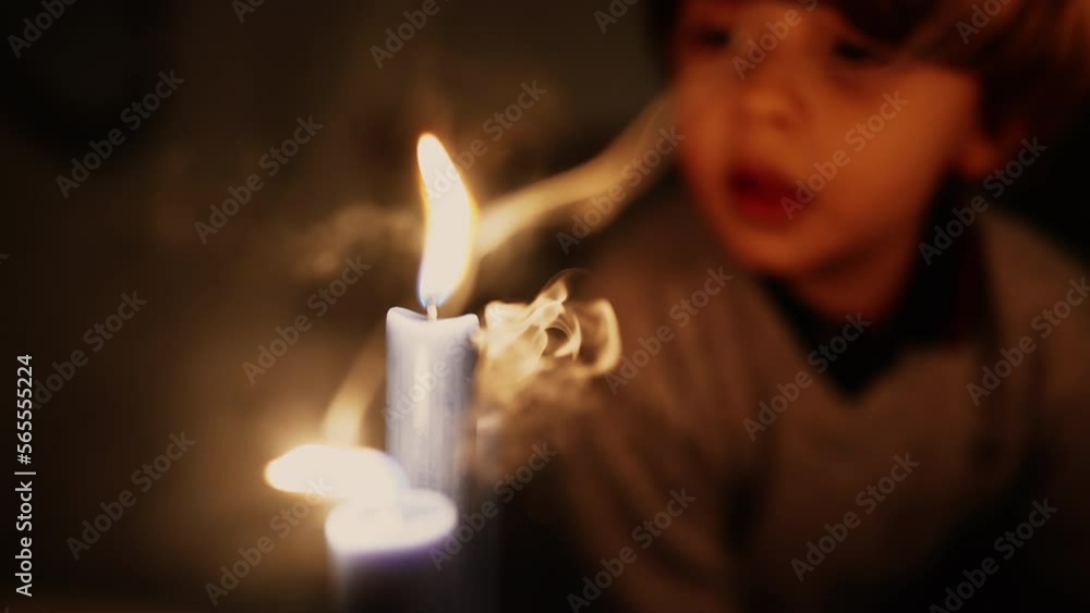 Little boy blows candle light in slow motion at night. Child making a wish blowing burning candlelight Little boy blows candle light in slow motion at night. Child making a wish blowing burning candlelight