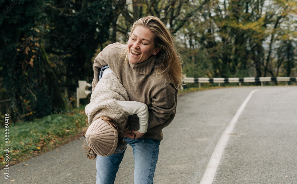 Laughing mother circling her little daughter in her arms on a rural road. Laughing mother circling her little daughter in her arms on a rural road.