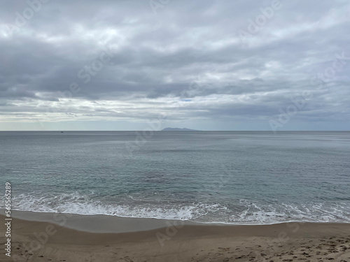 Sand beach, blue sea and an island on background. Coastline of Homunga Bay, Waikato region, New Zealand.
