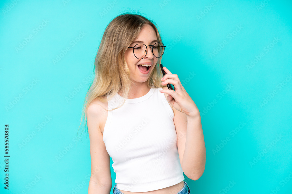 Blonde English young girl isolated on blue background using mobile phone and singing Blonde English young girl isolated on blue background using mobile phone and singing