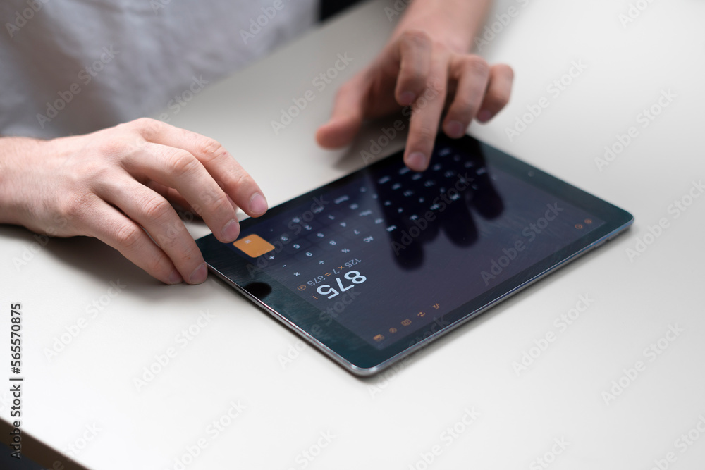 person holding a digital tablet and using a calculator person holding a digital tablet and using a calculator