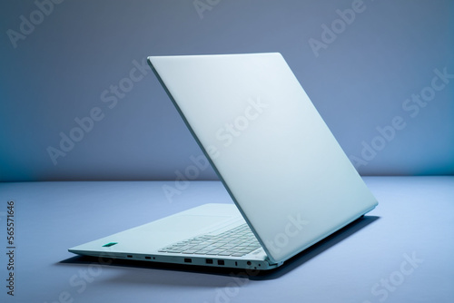 Side view of slim laptop and hands with wireless headphones on grey desk. Blue background. Distant learning. working from home, online courses or support. Audio podcast. vlogger or blogger banner