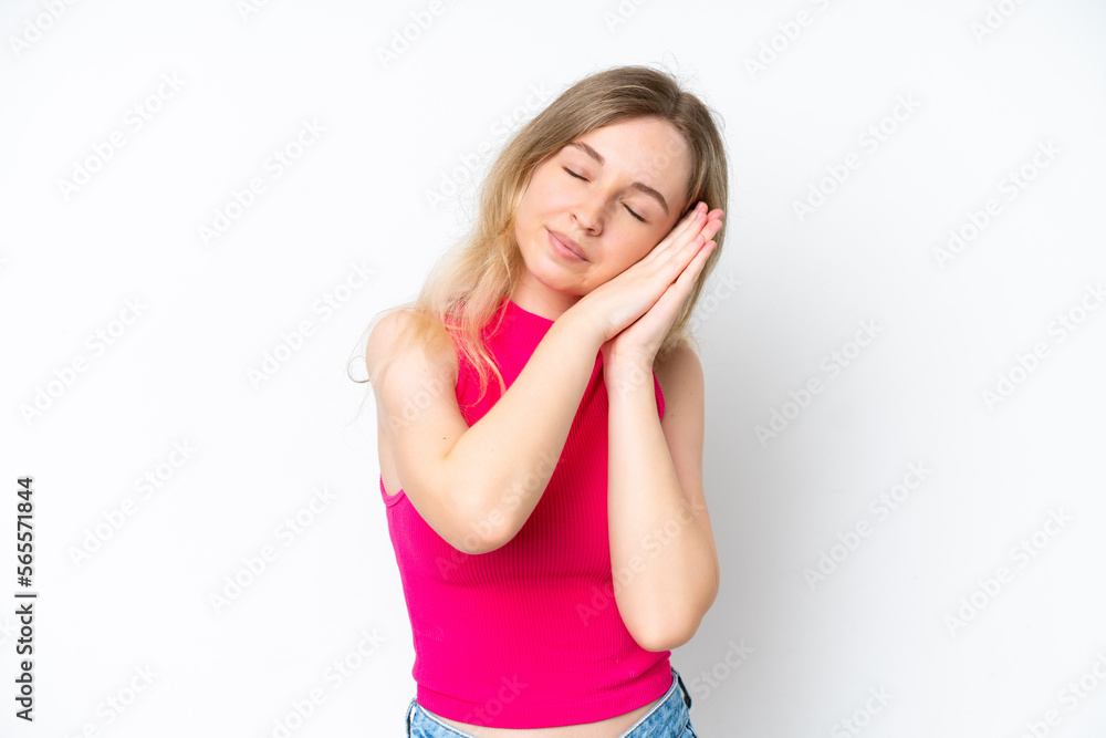 Blonde English young girl isolated on white background making sleep gesture in dorable expression Blonde English young girl isolated on white background making sleep gesture in dorable expression