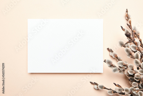 Greeting card mockup with spring floral decor on beige background, top view, flat lay. Blank Easter Holiday card with soft fluffy catkins photo