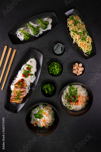 Various dishes of Asian cuisine with different types noodles and rice with shrimp, duck, vegetables and black sesame