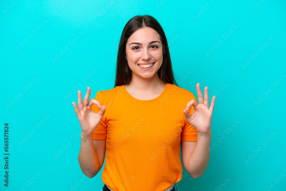Young caucasian woman isolated on blue background showing ok sign with two hands Young caucasian woman isolated on blue background showing ok sign with two hands