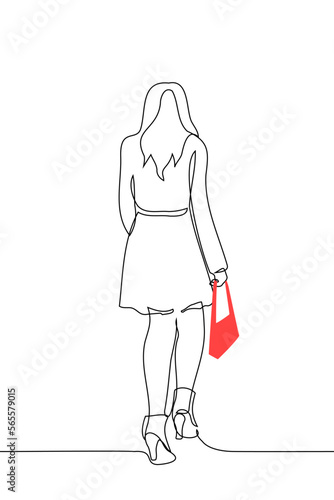 woman in a coat with long hair walks in ankle boots with a red handbag - one line drawing vector. concept fashionista, model, street fashion