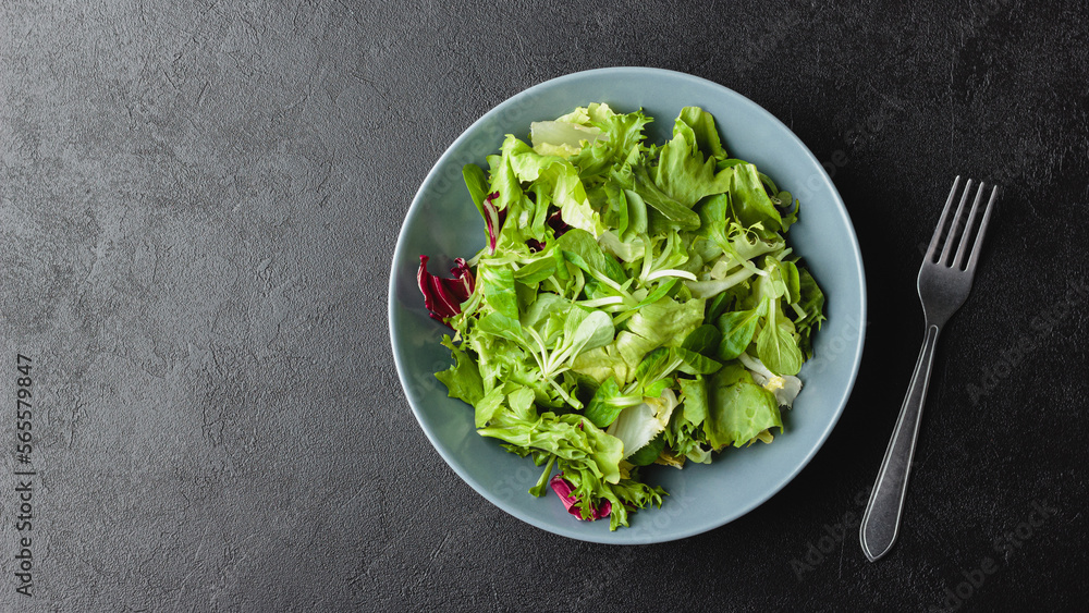 Green salad leaves in bowl on black table. Green salad leaves in bowl on black table.