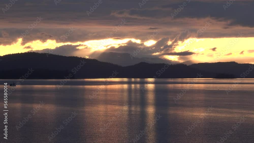 Beautiful golden sunset . Orange light in front of the mountains. Sunset, silhouette of a mountain range with dark blue sky background. Beautiful traveling. Shot from a traveling cruise ship. Beautiful golden sunset . Orange light in front of the mountains. Sunset, silhouette of a mountain range with dark blue sky background. Beautiful traveling. Shot from a traveling cruise ship.