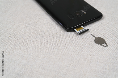Sim ejector tool and SIM card slot of smartphone on fabric background