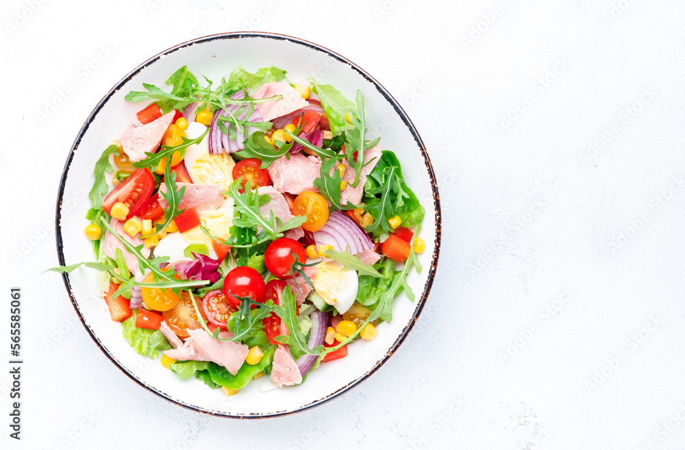 Fish tuna and fresh vegetables salad with cherry tomatoes, red onion, eggs, corn, paprika, lettuce, radicchio and arugula. White table background, top view Fish tuna and fresh vegetables salad with cherry tomatoes, red onion, eggs, corn, paprika, lettuce, radicchio and arugula. White table background, top view