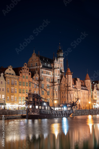 Night image of the river and the buildings of the city of Gdansk (Poland) illuminated, capturing the reflection of the water with a medieval ship. © Fuentes RAW