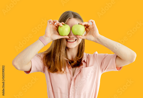 Woman in kitchen ready to prepare meal with vegetables and fruits. Woman is holding apples near her eyes. Kitchen background. © Vadim