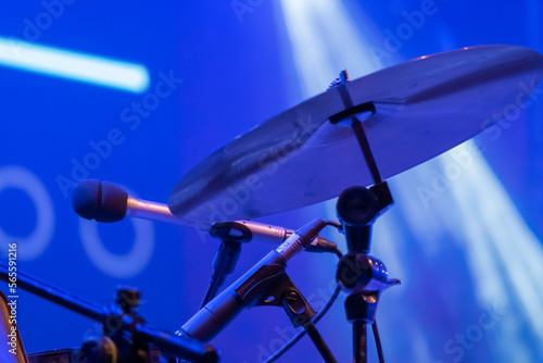 A kit of drums and a microphones on an empty stage.
