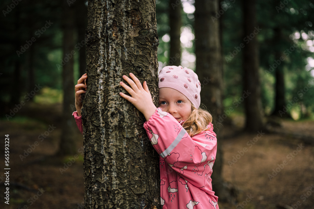 Blonde child in forest smiling and hugging tree Blonde child in forest smiling and hugging tree