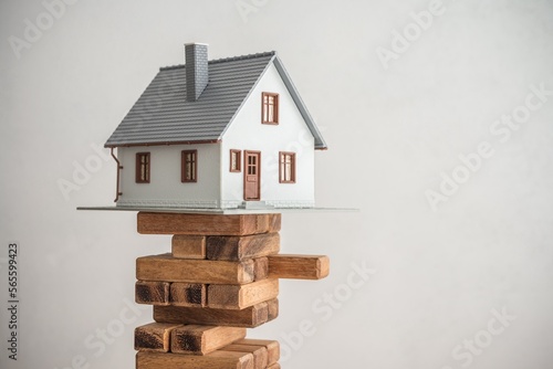 Modern house on wood tower block game white wall background copy space. Mortgage loan for buying home or real estate property, money risk management in financial, foreclosure and bankruptcy  concept photo