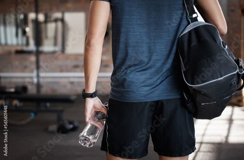 Exercise, bag and back of man in gym ready to start workout. Sports, fitness and hands of male athlete with water bottle for hydration and preparing for training and exercising for health or wellness photo