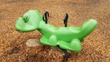green animal ride at playground with wood chips