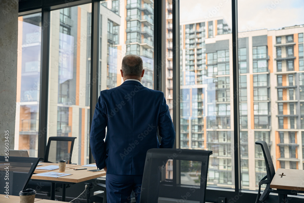 Stylish man enjoying view from the modern office window Stylish man enjoying view from the modern office window