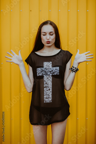 teenage girl with long hair poses; slender figure of a beautiful girl with emotional facial expressions; sunglasses on the head; a person against the background of a city landscape;