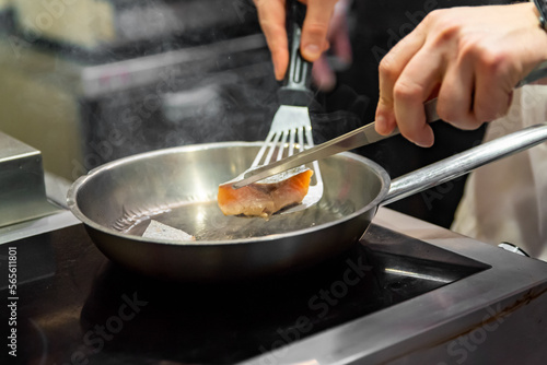 man chef cooking fried salmon fish in frying pan on kitchen