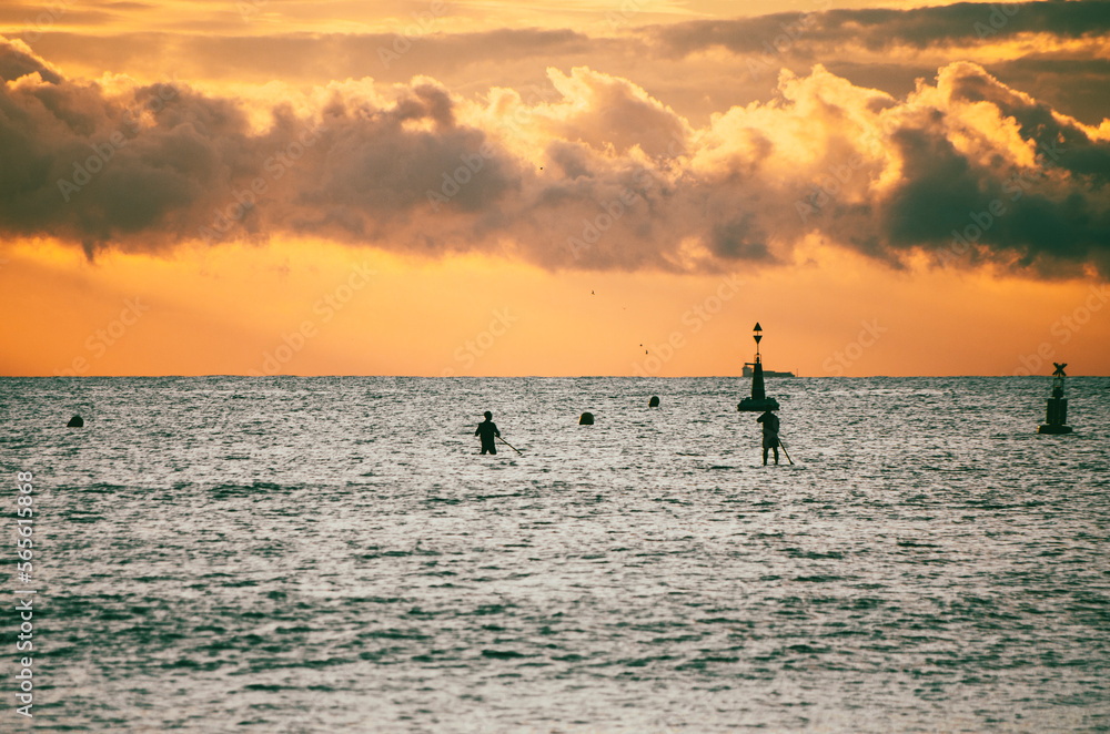 Fototapeta premium Silhouette of people doing stand up paddle at sunrise