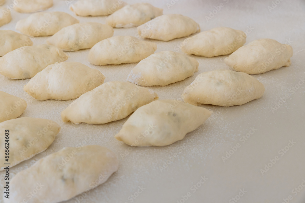 Making homemade buns from yeast dough on white countertop, using potatoes as filling