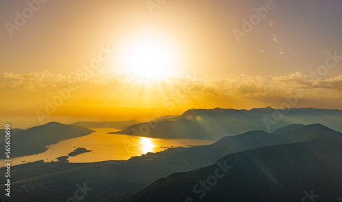 Dazzling sun in the evening sky illuminates all the peaks of the Balkan Montenegrin mountains and the coast of Kotor Bay