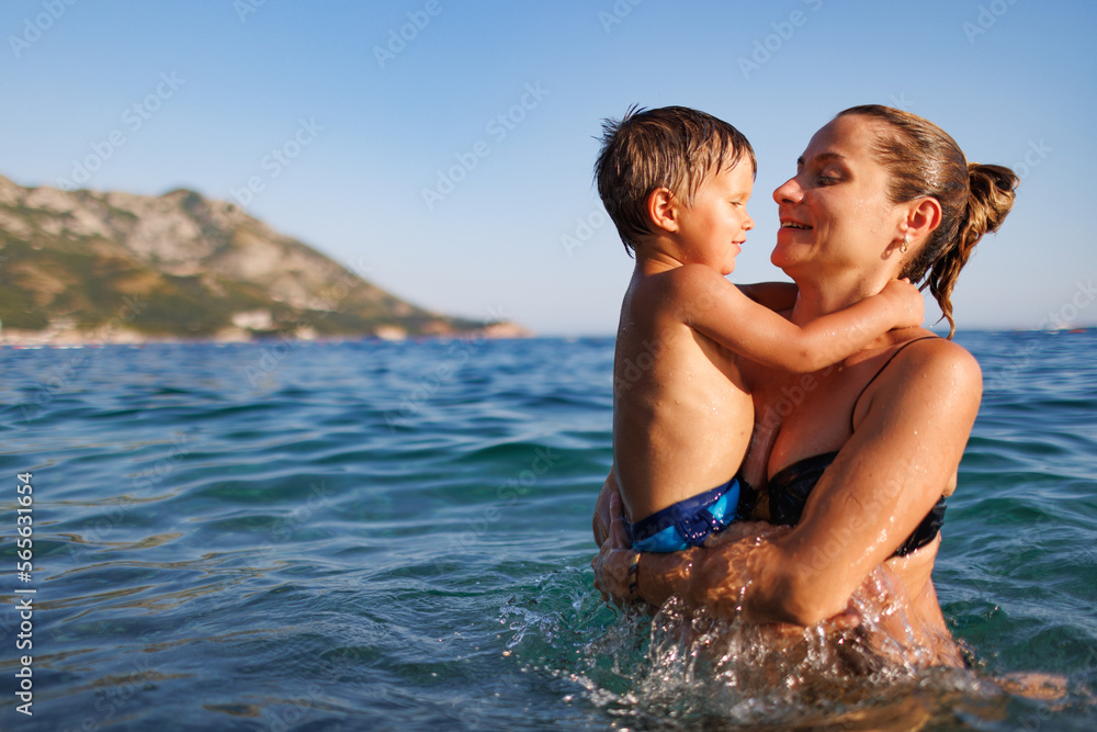 Cheerful mother plays with her son in the sea Cheerful mother plays with her son in the sea