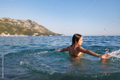 A teenage girl spins in a circle and makes circles with her hands on the surface of the water
