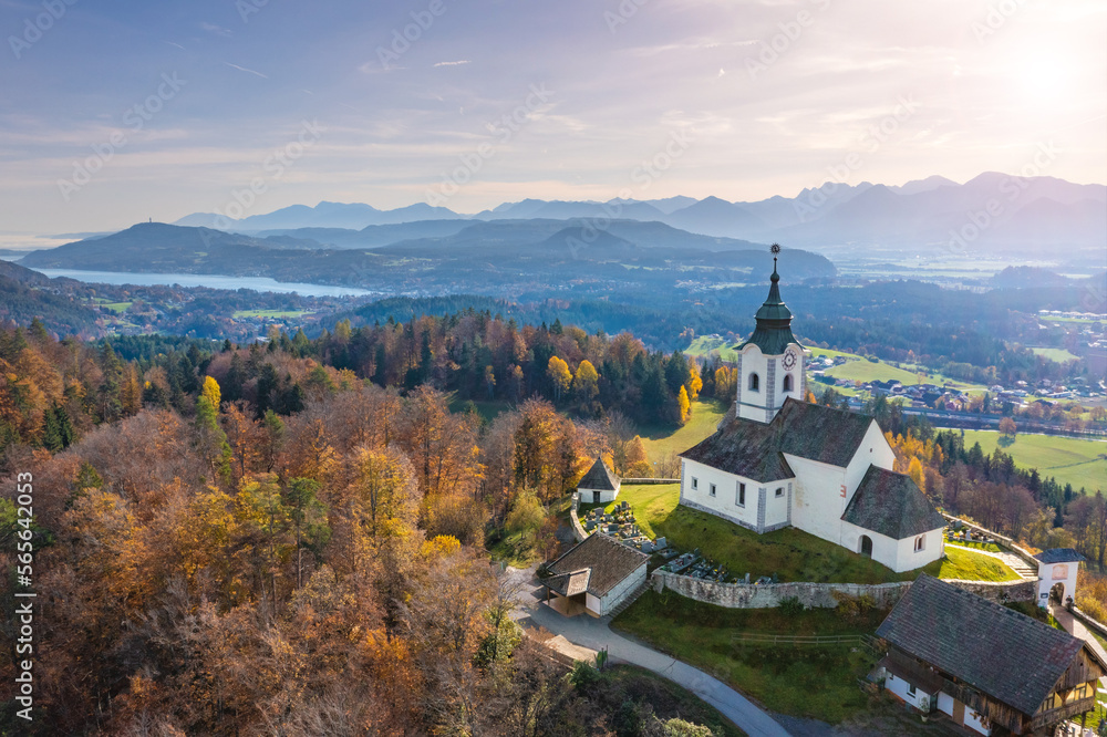 Sternberg church and idyllic graveyard in Wernberg, Carinthia, Austria during autumn with a view to Lake Wörthersee in the background.