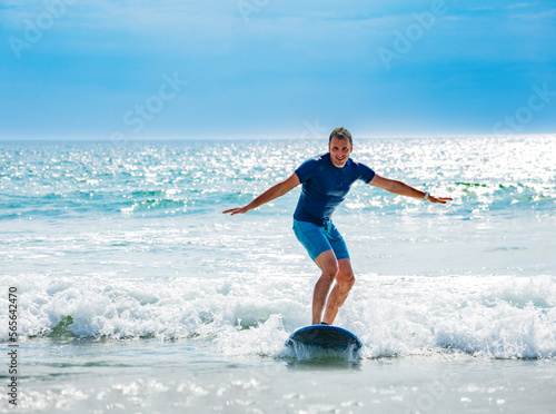 Man learns to surf waves balancing on surfboard © Sergey Novikov