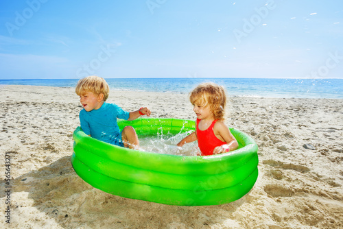 Kids play splashing in the inflatable pool at beach © Sergey Novikov