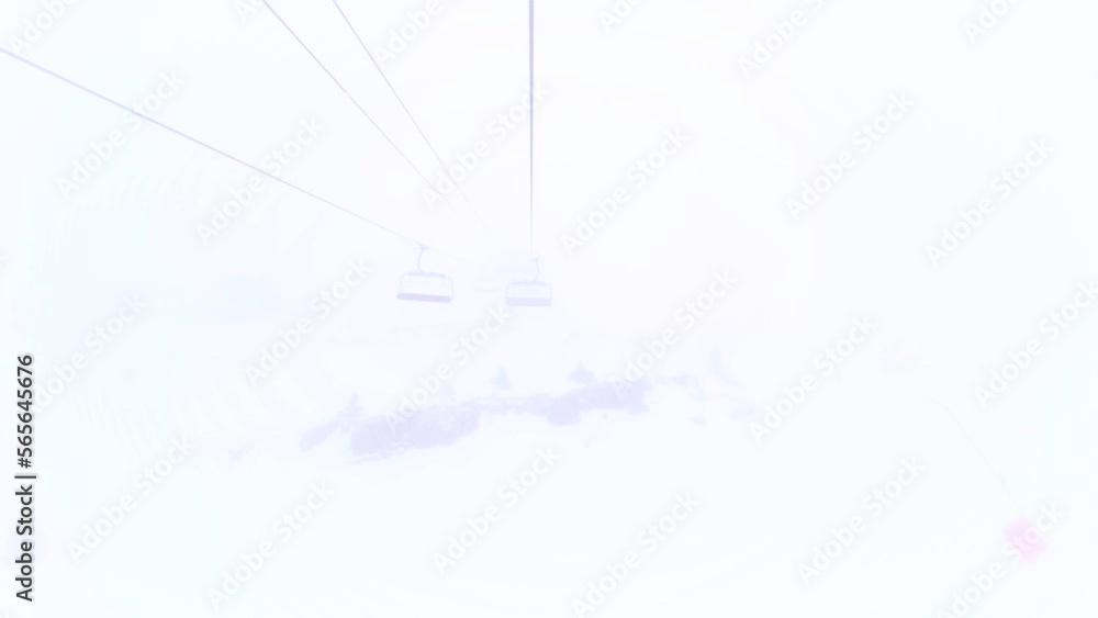 Six person chairlift on steel cable moving in clouds. Foggy weather in ski resort. Six person chairlift on steel cable moving in clouds. Foggy weather in ski resort.