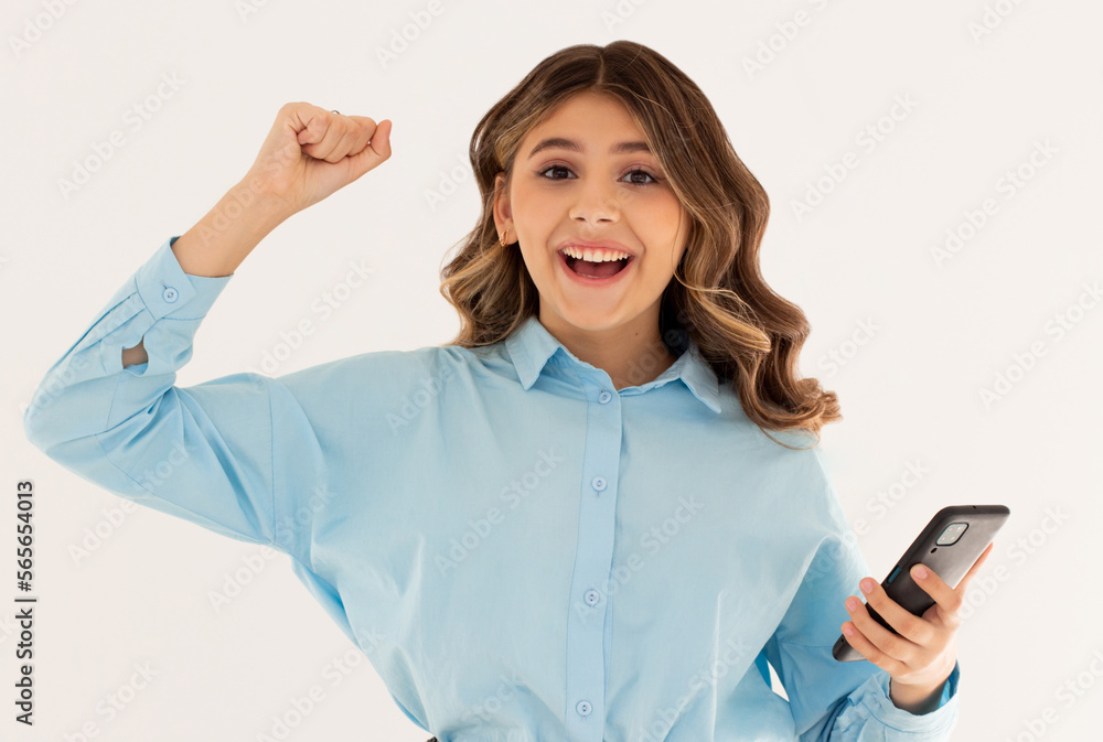 Portrait of a happy excited girl holding mobile phone and celebrating win isolated over white background Portrait of a happy excited girl holding mobile phone and celebrating win isolated over white background