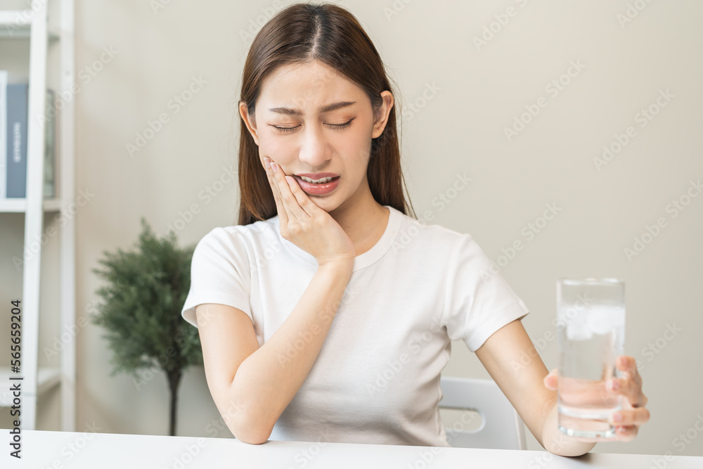Suffering from toothache, asian young woman, girl touch cheek, face expression ache or feel pain, sensitive molar teeth, hand holding glass of water with ice, inflammation when drink cold, healthcare. Suffering from toothache, asian young woman, girl touch cheek, face expression ache or feel pain, sensitive molar teeth, hand holding glass of water with ice, inflammation when drink cold, healthcare.