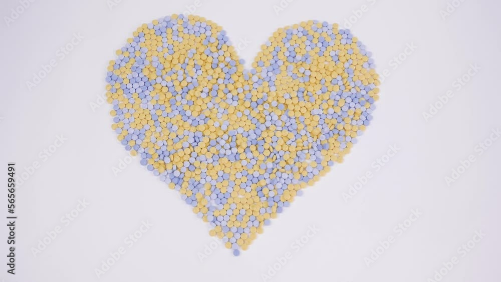 Yellow-blue pills laid out in the shape of a heart on a white background 4K Macro Zoom Rotation Yellow-blue pills laid out in the shape of a heart on a white background 4K Macro Zoom Rotation