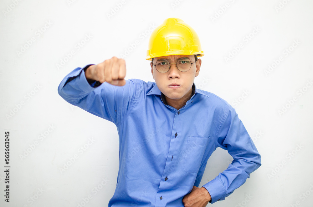 asian male construction worker or engineer in blue shirt and safety yellow helmet shows expresion of anger, furious and dissapointment isolated over white. stressed over work concept