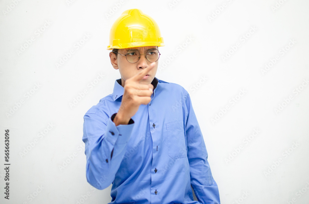 asian male construction worker or engineer in blue shirt and safety yellow helmet shows expresion of anger, furious and dissapointment isolated over white. stressed over work concept asian male construction worker or engineer in blue shirt and safety yellow helmet shows expresion of anger, furious and dissapointment isolated over white. stressed over work concept
