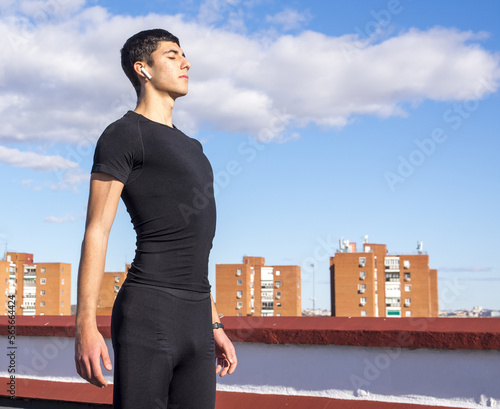 Strong yooung man relaxing breathing fresh air on a roof in a cloudy day listening to music photo