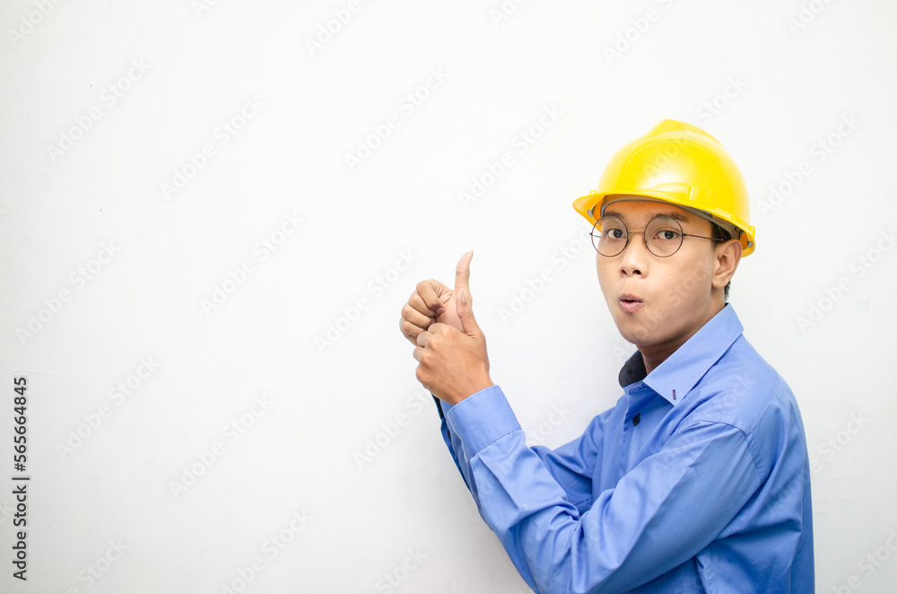 asian construction worker wearing yellow safety helmet and smiling and pointing finger with happy and shocked expression. billboard model advertisment concept. construction worker presenting something asian construction worker wearing yellow safety helmet and smiling and pointing finger with happy and shocked expression. billboard model advertisment concept. construction worker presenting something